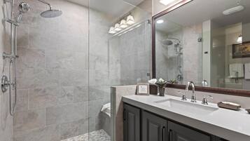Un baño moderno con ducha, lavamanos y un espejo grande.