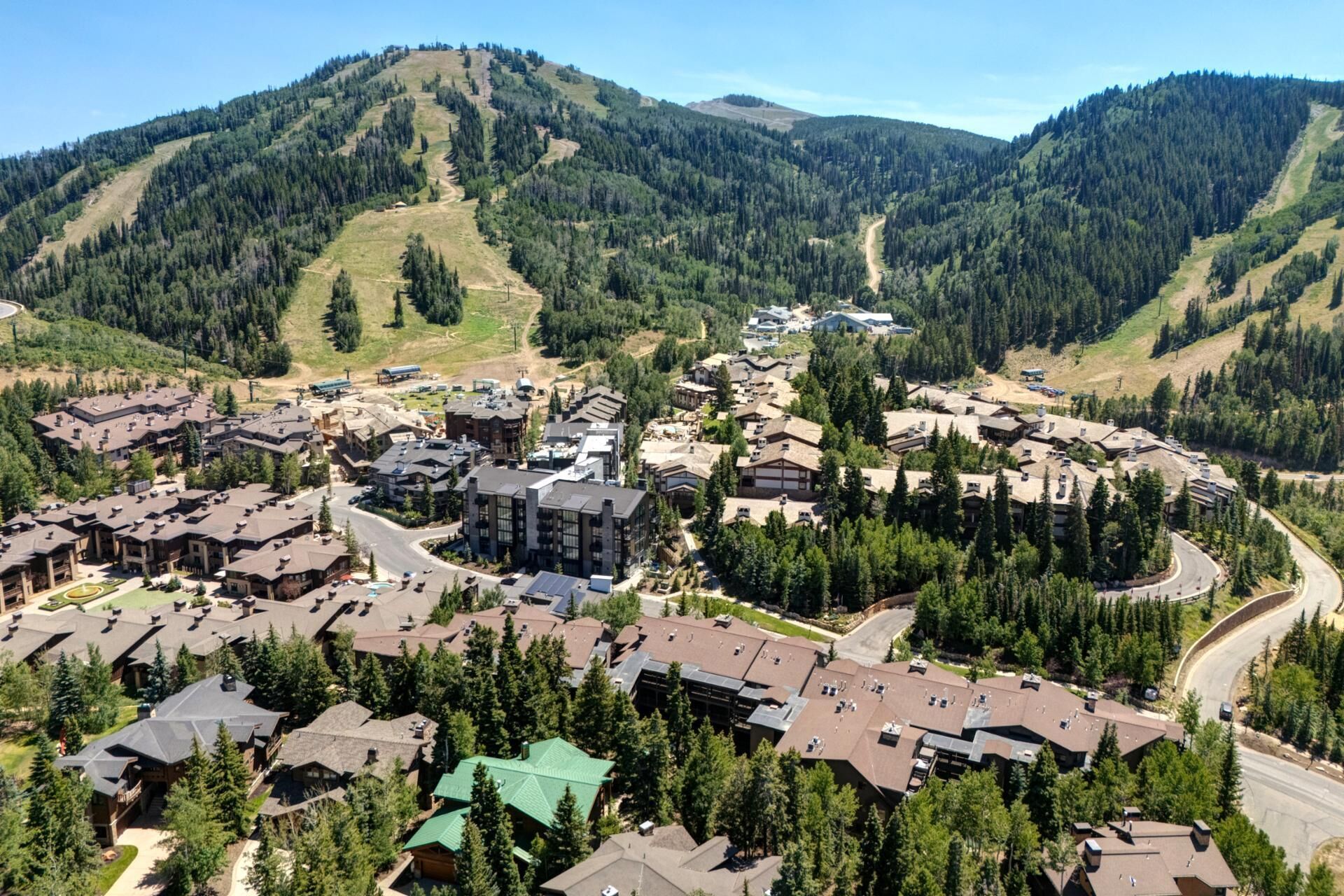 A mountain resort with multiple buildings, roads, and a forested backdrop.