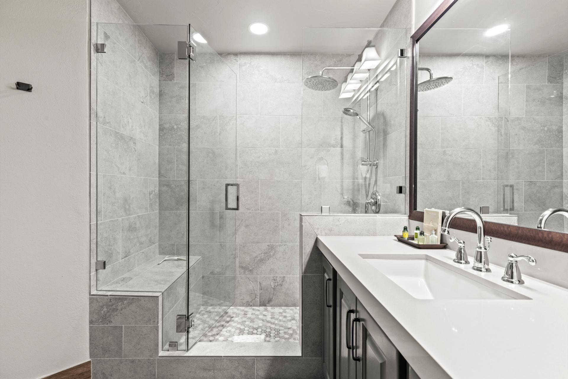 A modern bathroom with a glass-enclosed shower, a large mirror, and a vanity with two sinks.