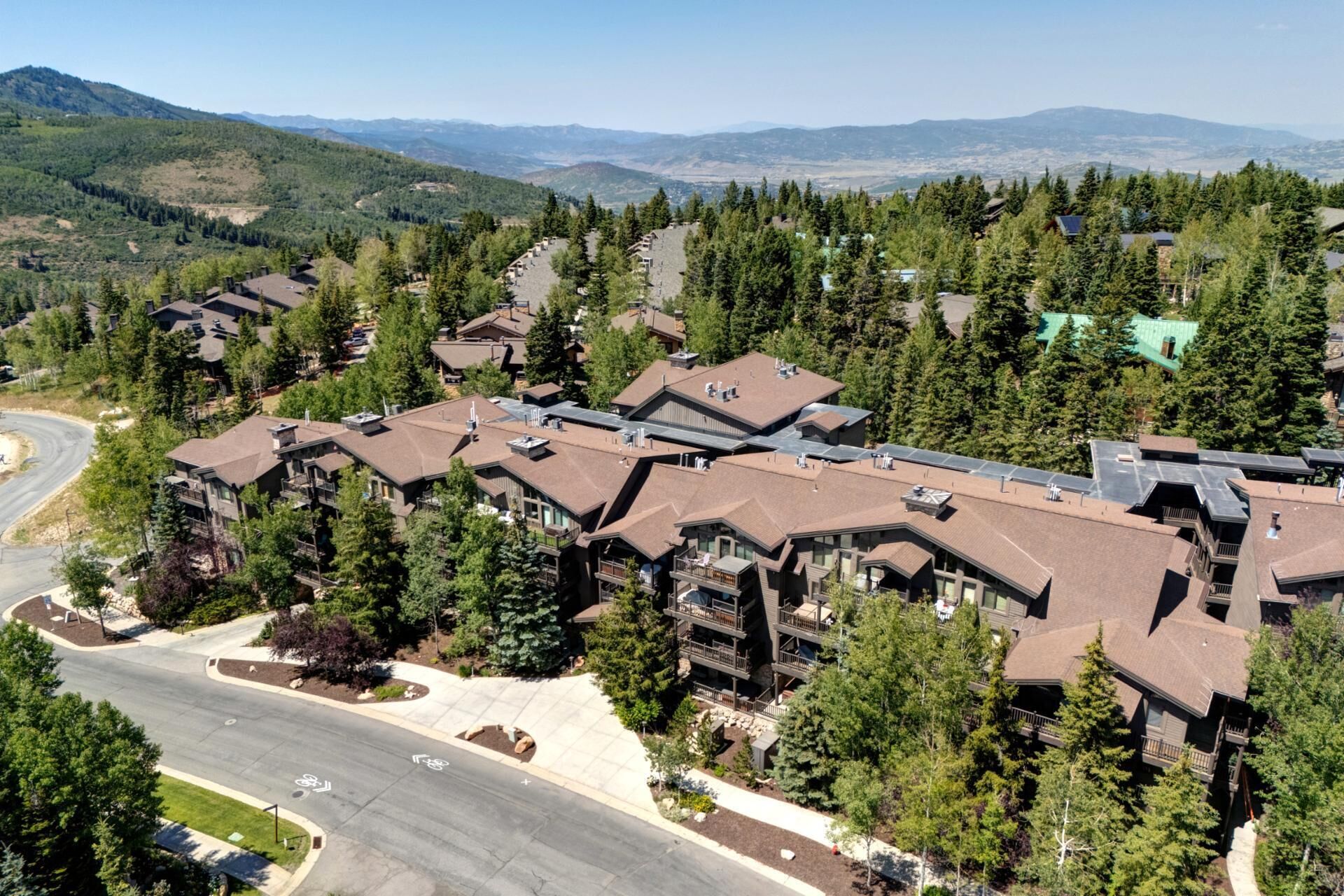 A residential area with multiple two-story houses, a winding road, and a backdrop of mountains.