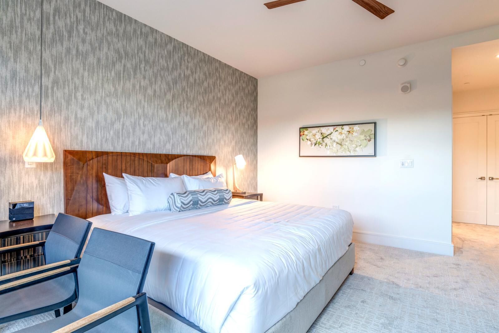 A modern hotel room with a large bed, a desk, and a chair.