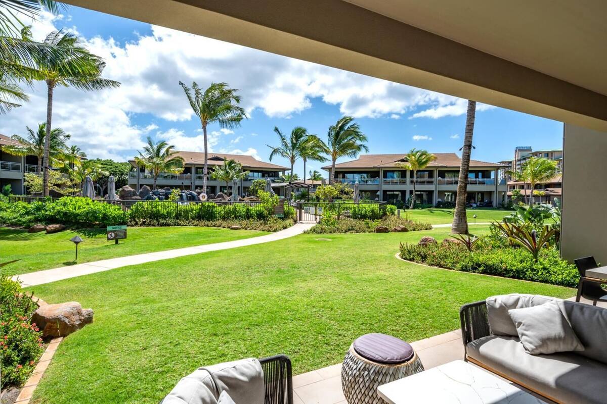 A hotel courtyard with a lawn, outdoor seating, and a view of the surrounding buildings.