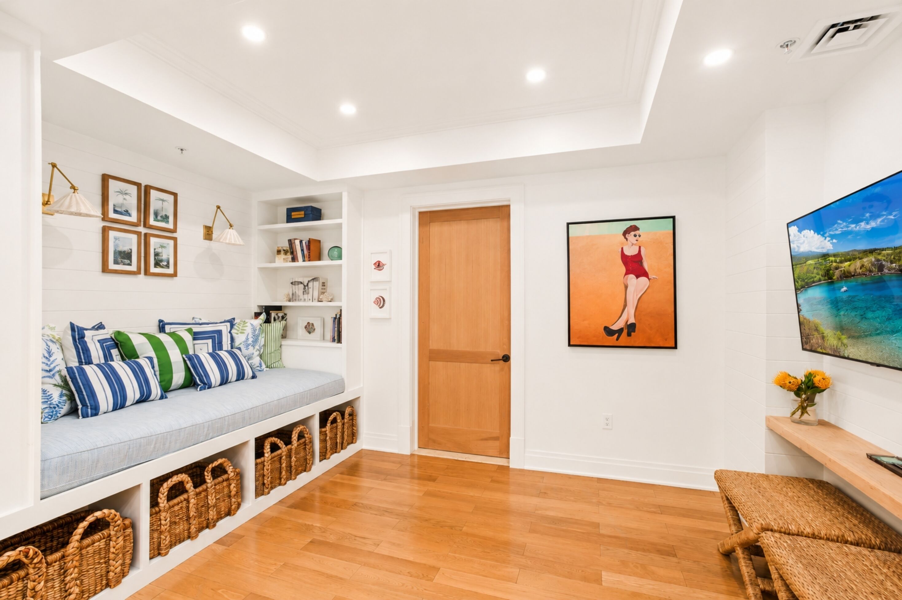 Interior moderno com piso de madeira, um banco embutido com cestos de armazenamento, uma estante e uma pintura grande.