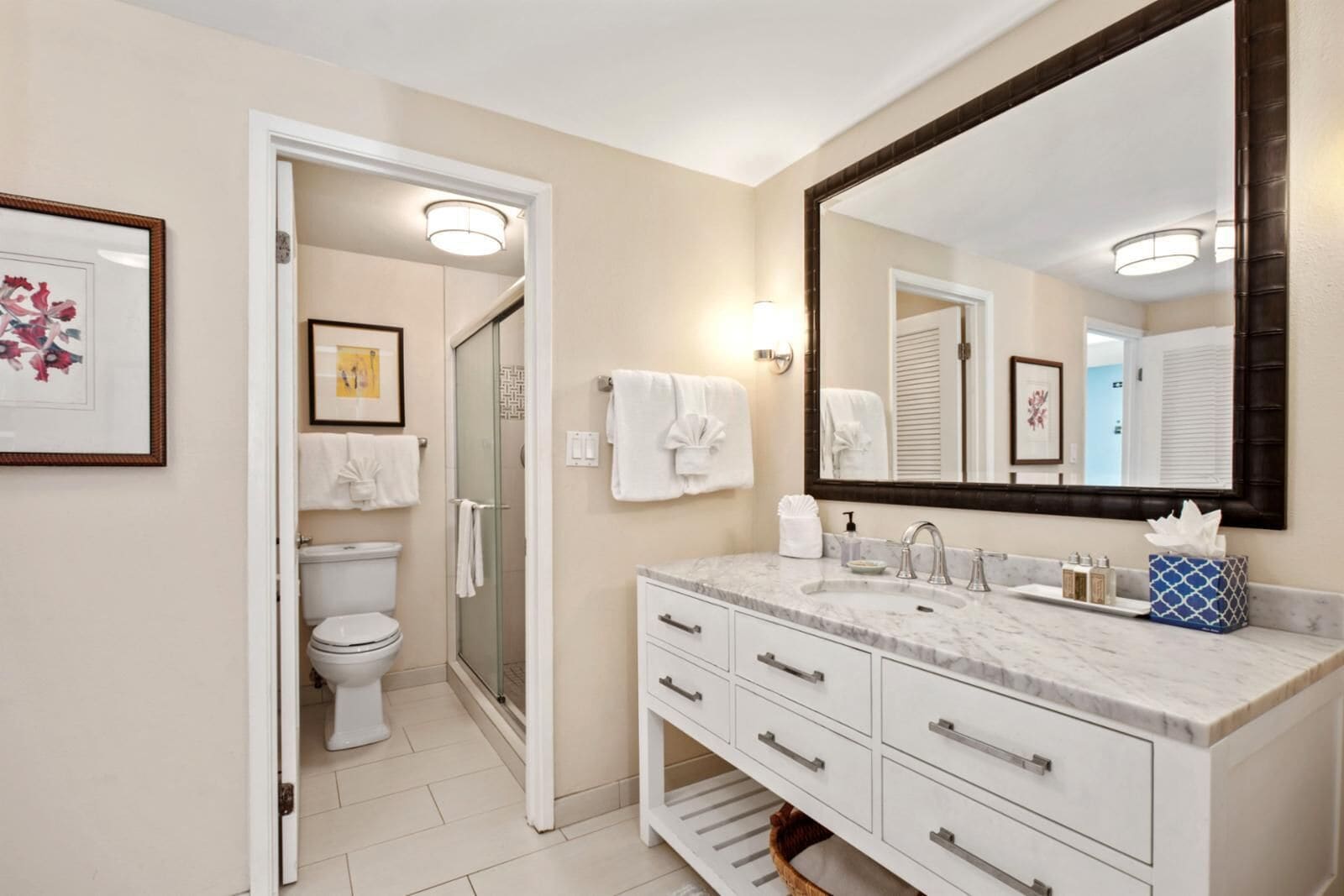 A modern bathroom with a glass shower, white fixtures, and a large mirror.