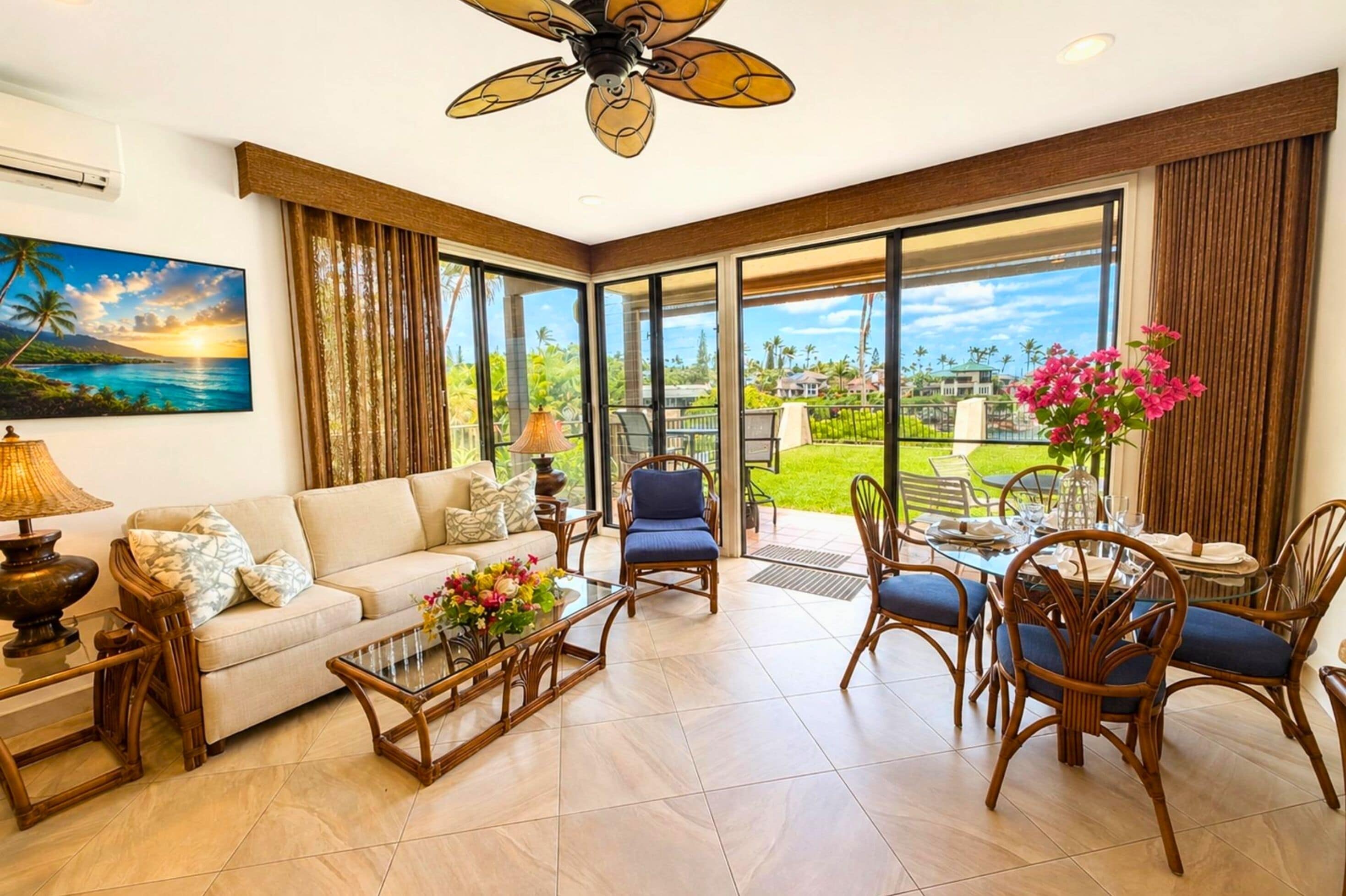A spacious living room with a sofa, coffee table, and chairs, large windows with a view of greenery and a sunset, and a ceiling fan.