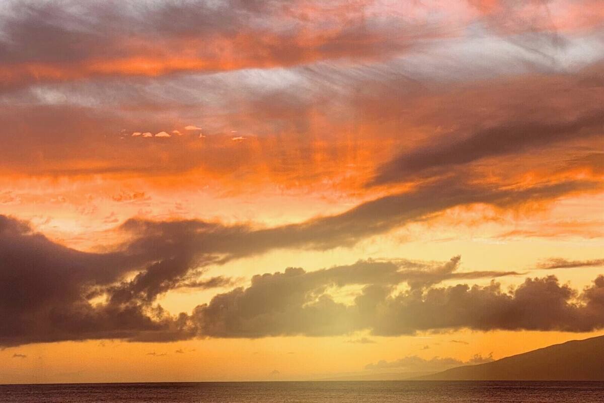 A sunset over a body of water with clouds.
