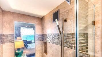 A modern shower with a glass enclosure, a tiled backsplash, and a visible vent.