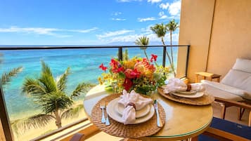 Un balcón con una mesa para dos, con vista a la playa y al océano.
