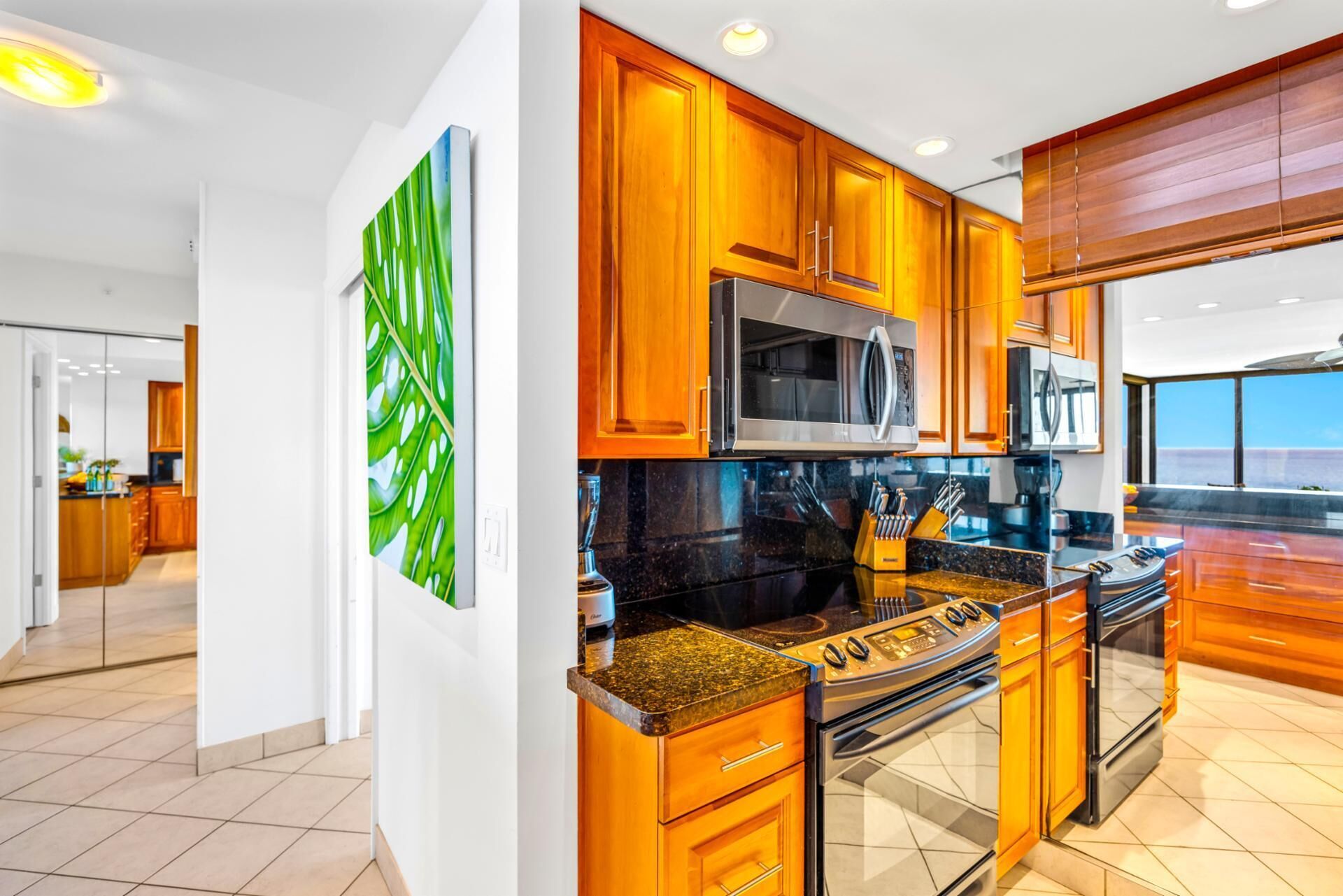 A modern kitchen with wooden cabinets, stainless steel appliances, and a large window.