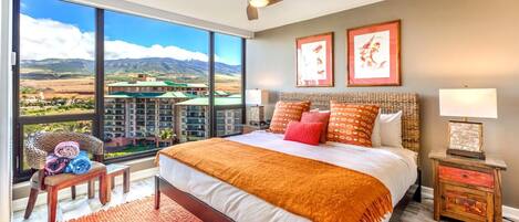 Un dormitorio amplio con una cama grande, vistas a montañas y un resort, y un ventilador de techo.