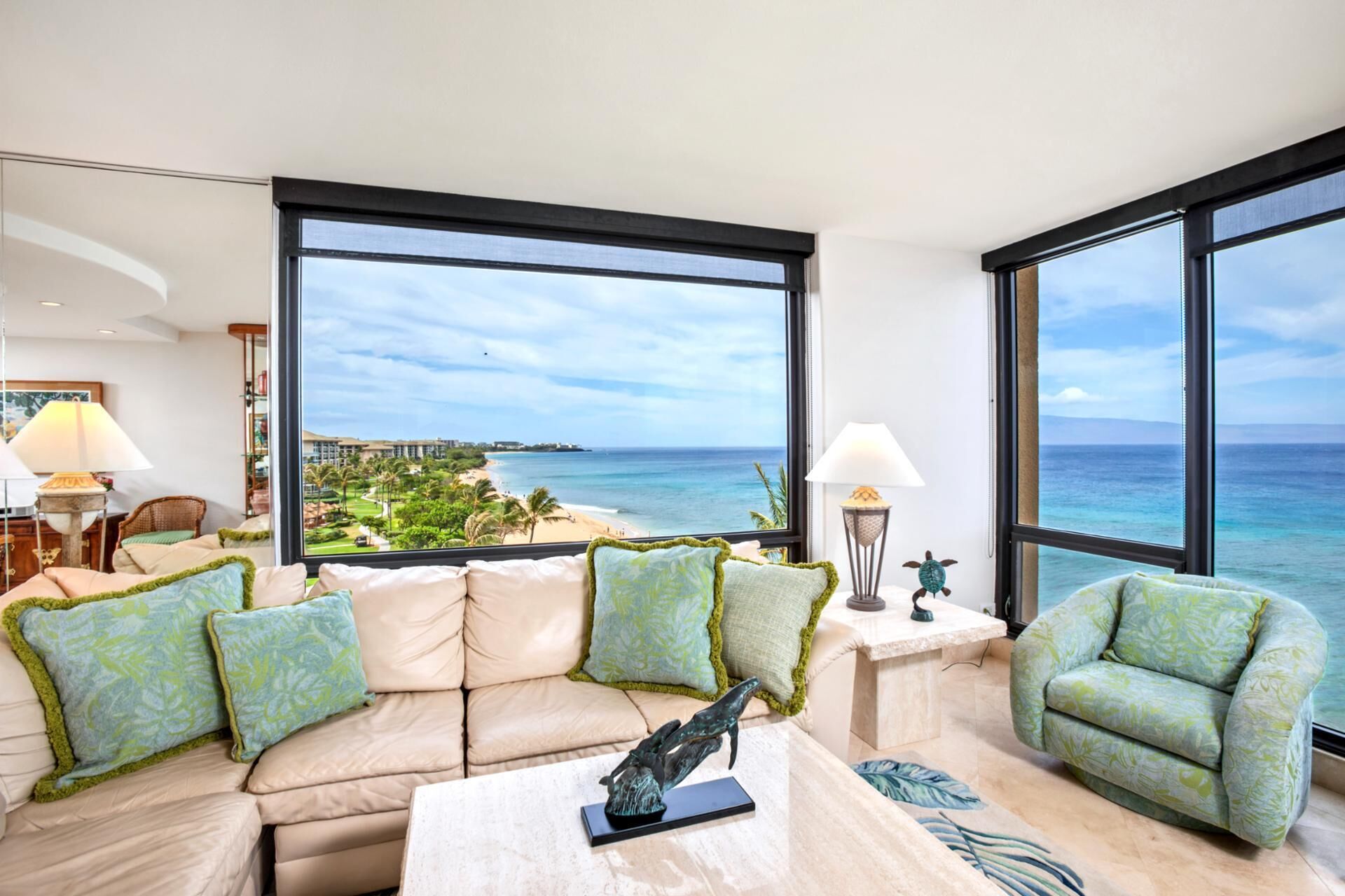 A modern living room with a large window offering a view of the beach and ocean.