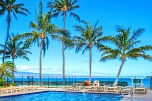 A pool area with palm trees and a view of the ocean. - Mahana Resort by KBM (Kaanapali)