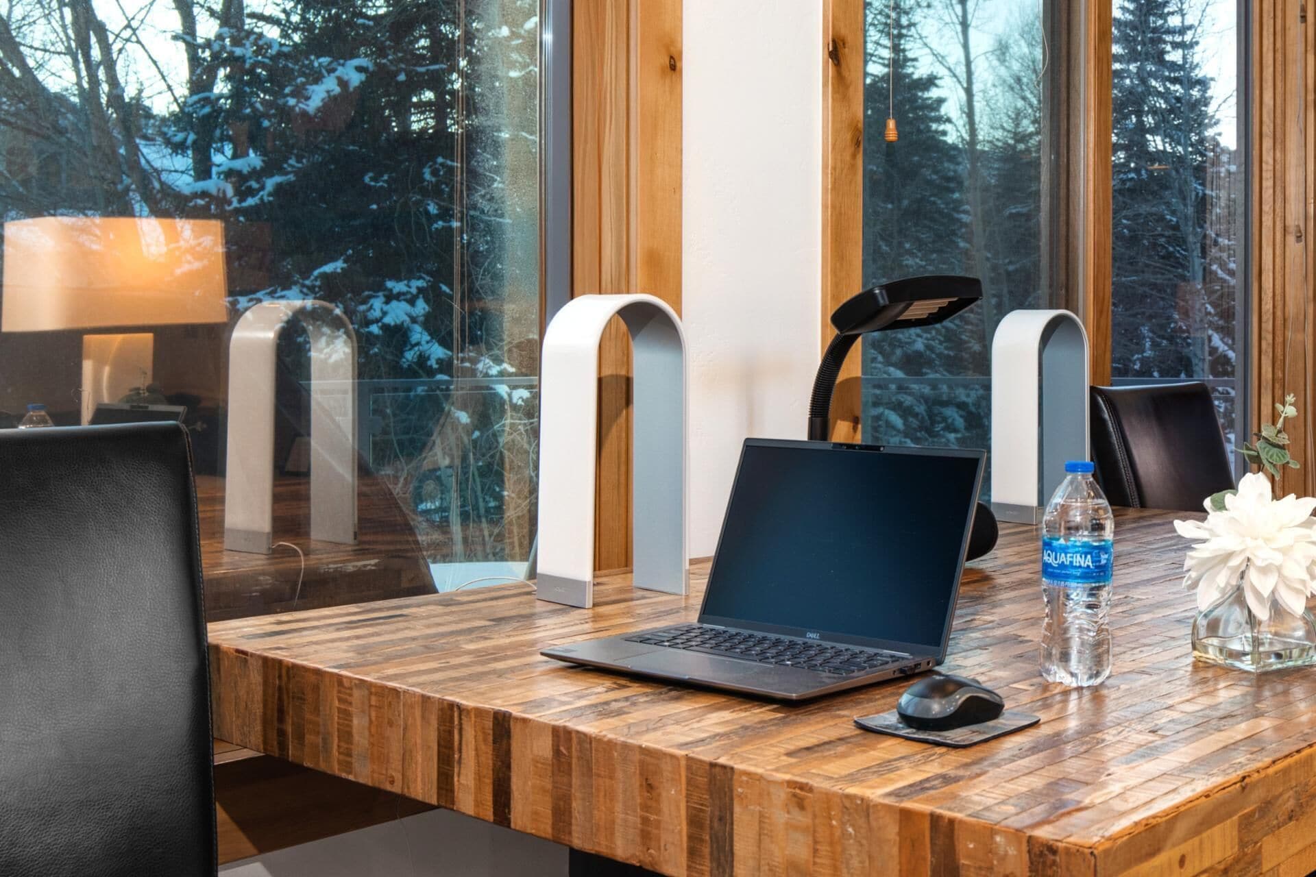 Ein Holztisch mit einem Laptop, einer Wasserflasche und einer dekorativen Vase.