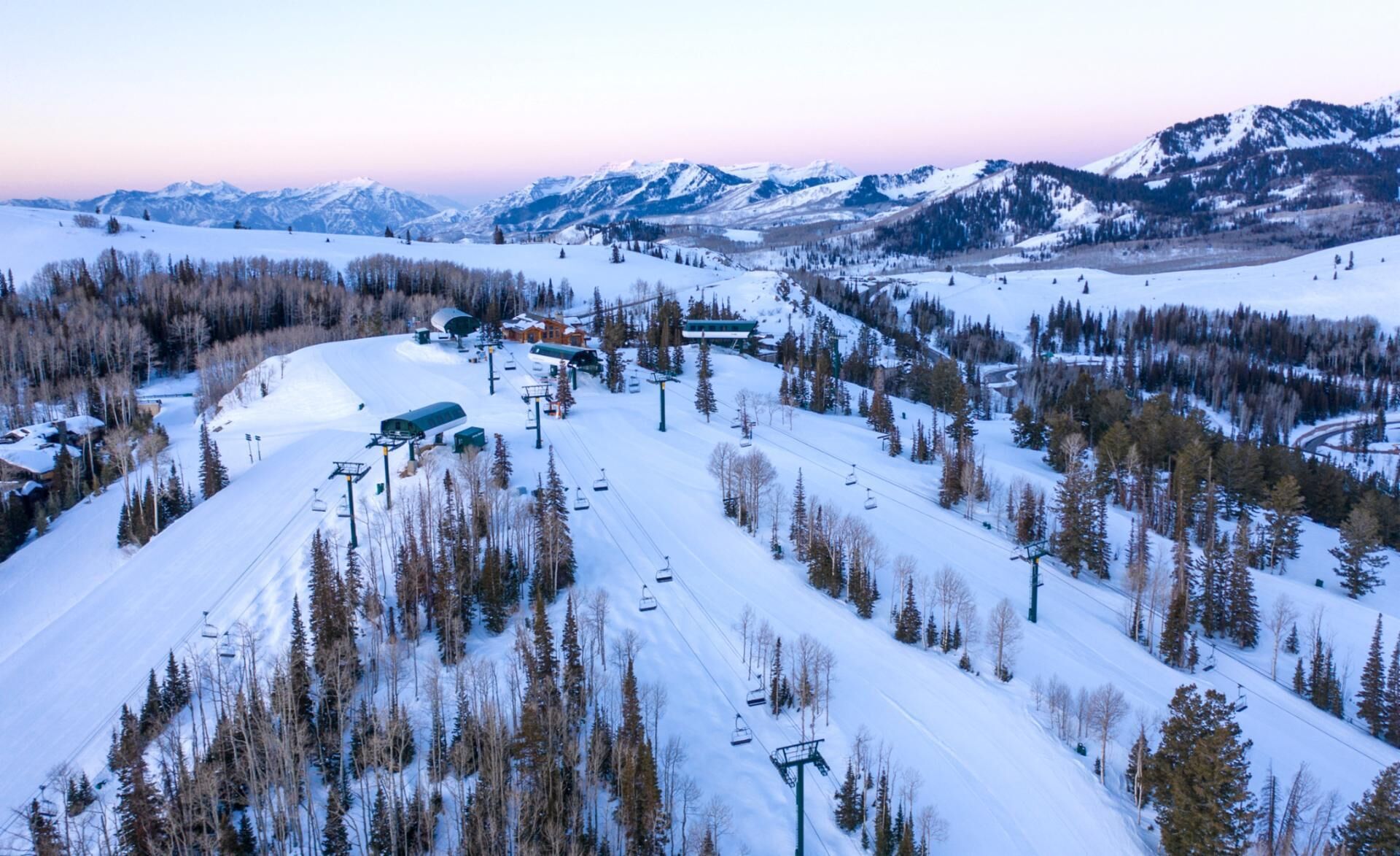 A ski resort with a chairlift, snow-covered slopes, and mountain views.