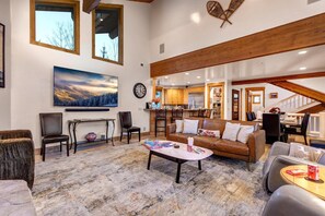 A spacious living area with a large painting, a dining area, and a kitchen.