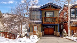 A two-story house with a front porch, a garage, and a snow-covered yard. - Norfolk Escape 3 Bedrooms PNF-860 by KBM (Park City)