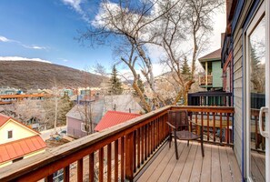 A wooden deck with a chair, overlooking a town with colorful buildings and a mountain in the background. - Norfolk Escape 3 Bedrooms PNF-860 by KBM (Park City)