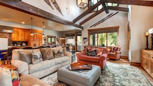 A spacious living area with a large sofa, a smaller sofa, and a coffee table. There is a kitchen in the background with wooden cabinets and a dining area. - Rossi Hill 4 Bedrooms PRH-685 by KBM (Park City)