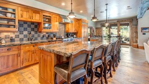 A spacious kitchen with wooden cabinets, granite countertops, and a large island with bar seating. - Rossi Hill 4 Bedrooms PRH-685 by KBM (Park City)