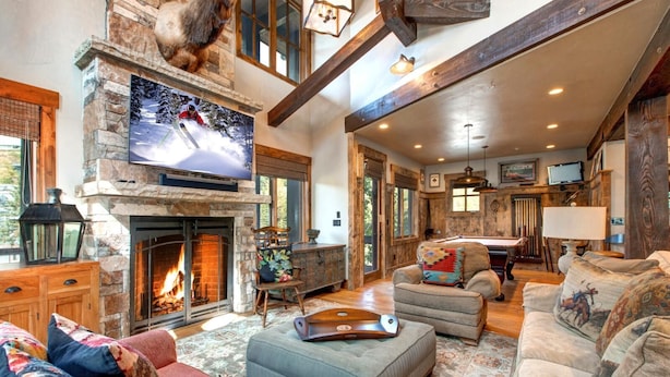 A spacious living room with a stone fireplace, a television mounted above it, and a cozy seating area with sofas and a coffee table. - Rossi Hill 4 Bedrooms PRH-685 by KBM (Park City)