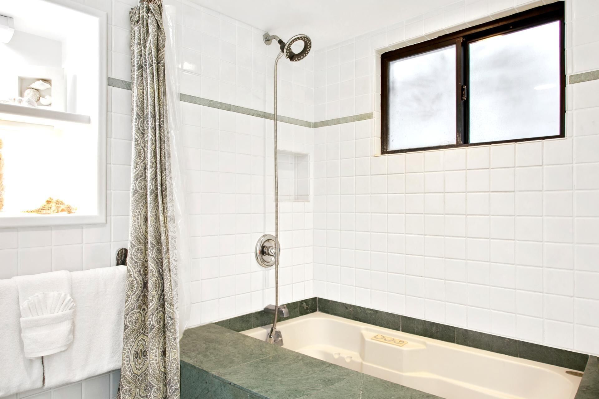 Un baño con ducha, bañera y ventana.