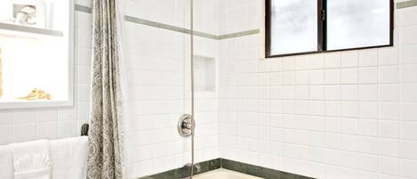 Un baño con ducha, bañera y ventana.