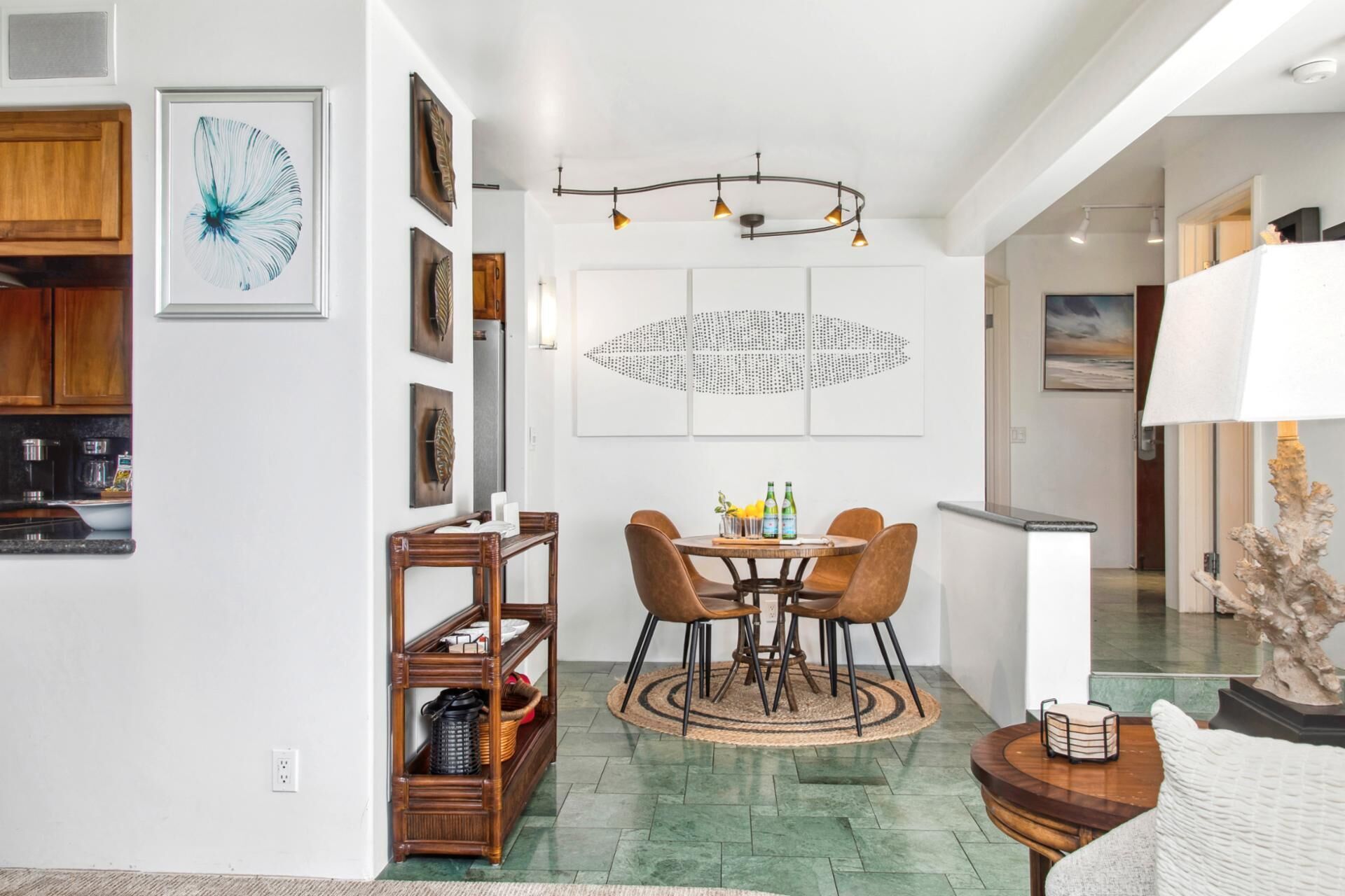 A dining area with a round table, four chairs, a chandelier, and artwork on the walls.