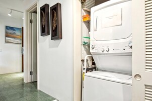 Un lavadero con lavadora y secadora, una puerta con picaporte, y un cuadro en la pared.