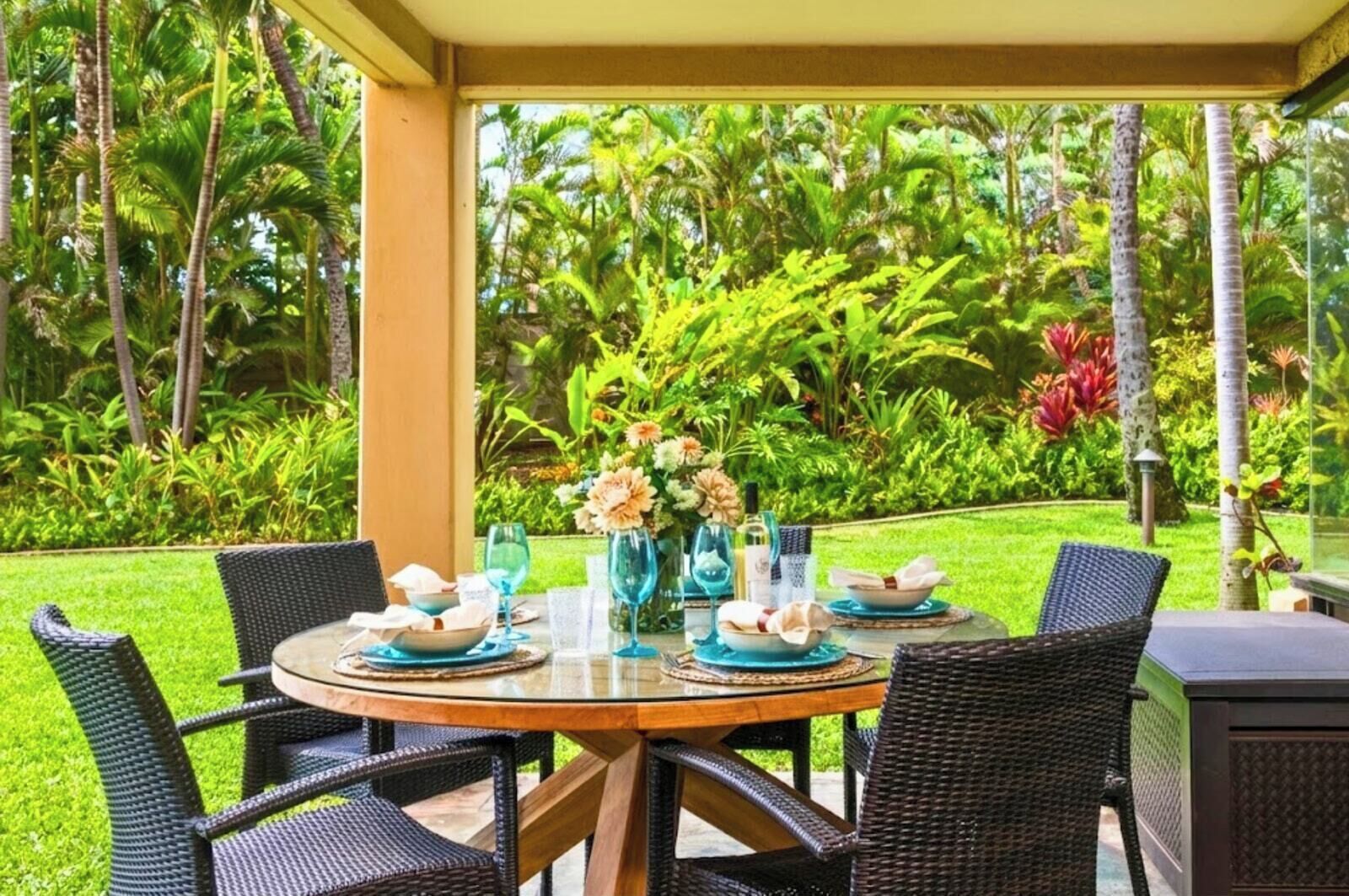 A round table with chairs, a glass top, and a floral centerpiece.
