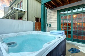 A hot tub in an outdoor setting with a wooden deck and a green door. - Park Avenue Townhomes by KBM (Park City)