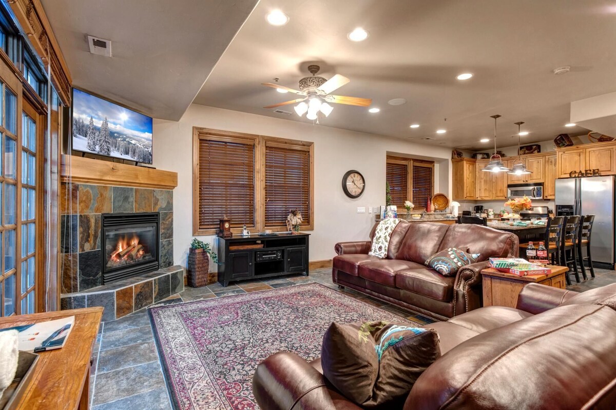 A living room with a fireplace, leather sofa, and a rug.