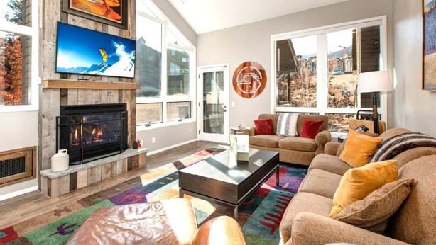 A living room with a fireplace, a large TV, and a sofa with cushions. - Red Pine 4 Bedrooms RPT-14T by KBM (Park City)