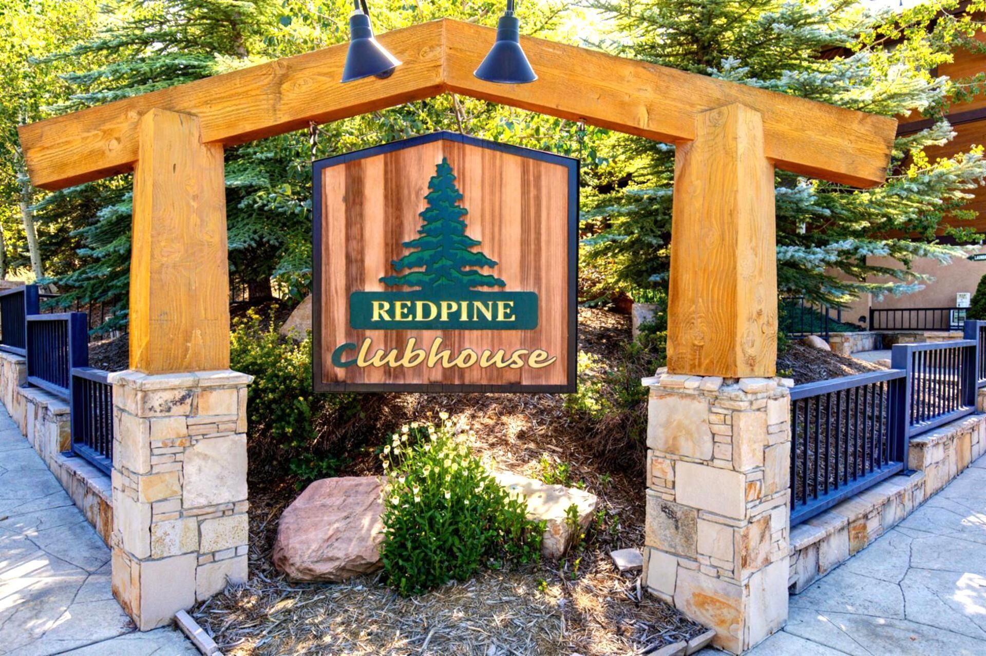 A wooden sign with a pine tree logo and the text 'REDPINE Clubhouse' under a wooden archway.