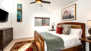 A bedroom with a wooden bed, a ceiling fan, a window, a TV, and artwork on the walls. - Red Pine 4 Bedrooms RPT-14T by KBM (Park City)