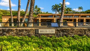 Un bâtiment moderne avec un mur en pierre et une enseigne indiquant « WAILEA ELUA ».