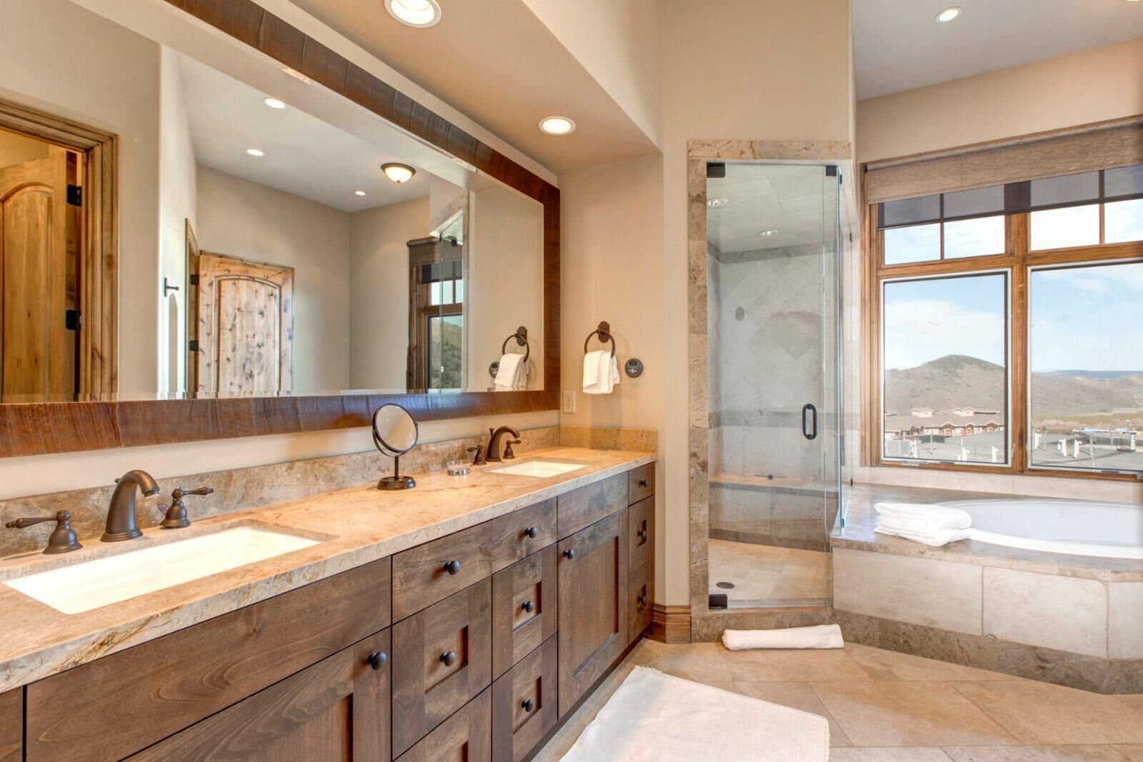 Une salle de bain avec deux lavabos, un grand miroir, un espace douche et une baignoire.
