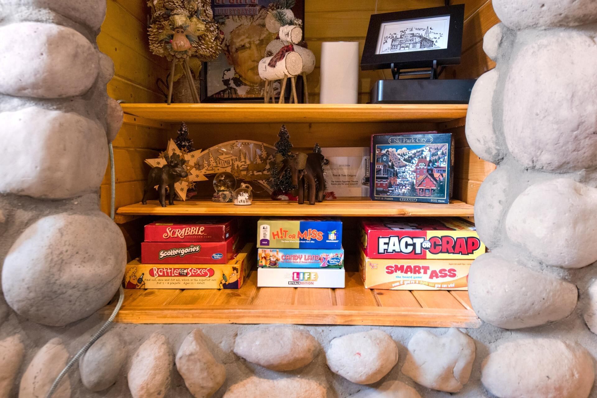 A shelf with various board games, including Scrabble, Candy Land, and Fact or Crap.