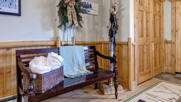 A wooden bench with a woven basket and towels, a wooden door, and a patterned rug.