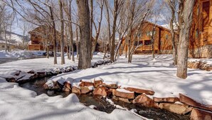 A wooden cabin with a stone stream in a snowy landscape. - Timber Wolf Lodge by KBM (Park City)