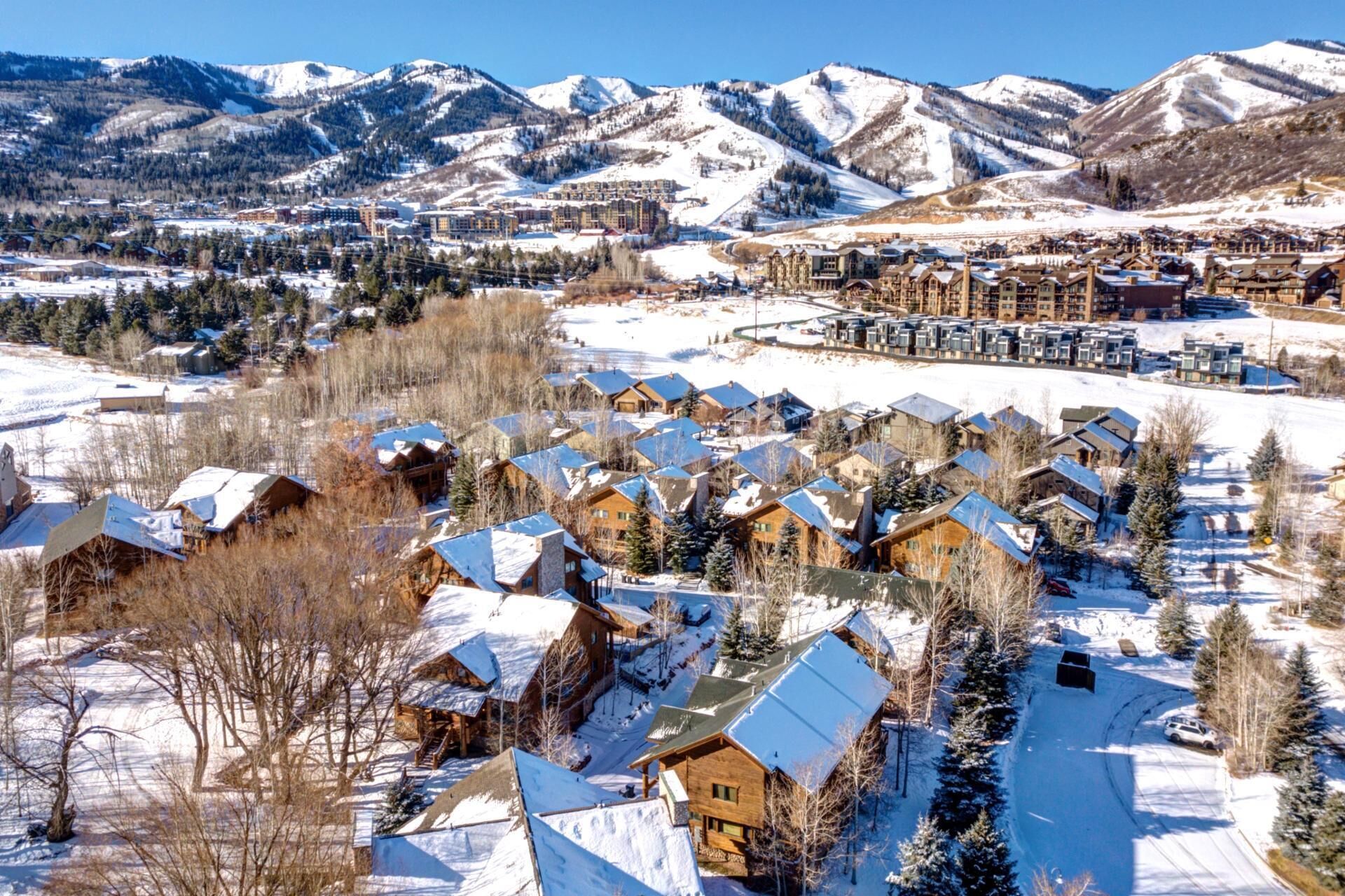A snow-covered village with wooden houses and a ski resort in the background.