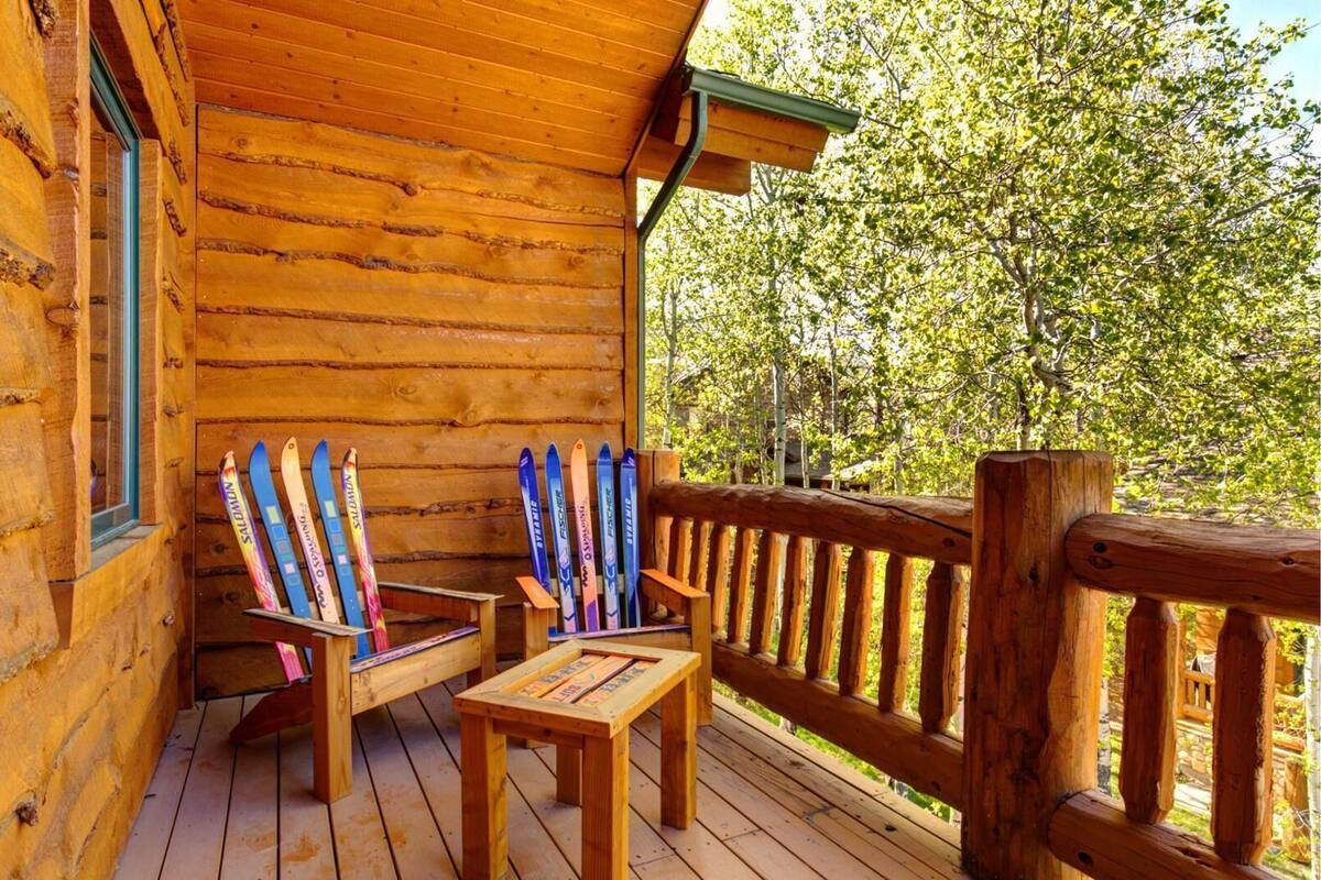 Eine Holzhütte mit einer Veranda, zwei Adirondack-Stühlen und Ski, die an der Wand lehnen.