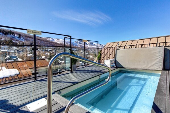 Una piscina en la azotea con un letrero que dice "NO CLIMBING", rodeada por una terraza de madera y una barandilla metálica.