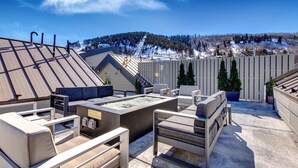 Terraza en la azotea con mobiliario exterior, bañera de hidromasaje y vistas a un paisaje montañoso nevado.