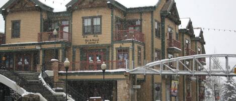 A multi-story building with a ski and board rental sign, a covered entrance, and a stone staircase.