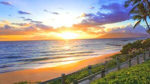 A sunset beach scene with a wooden walkway and palm trees. - Grand Champions by KBM (Kihei)