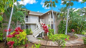 A two-story building with a white exterior and a covered outdoor area. - Grand Champions by KBM (Kihei)