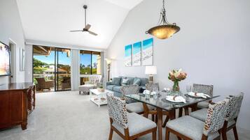 A spacious dining area with a glass table, wooden chairs, and a ceiling fan.