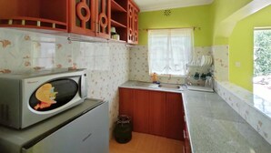 A compact kitchen with a microwave, a sink, and wooden cabinets. - Stay.Plus Lake View House Naivasha (Naivasha)