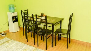 A dining area with a table and chairs, a water dispenser, and a power outlet on the wall. - Stay.Plus Lake View House Naivasha (Naivasha)