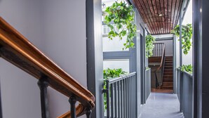 A narrow, modern hallway with a wooden handrail and metal railings, leading to a staircase with a wooden railing. - Incredible 2 Bedroom Apartment at El Rastro (Madrid)